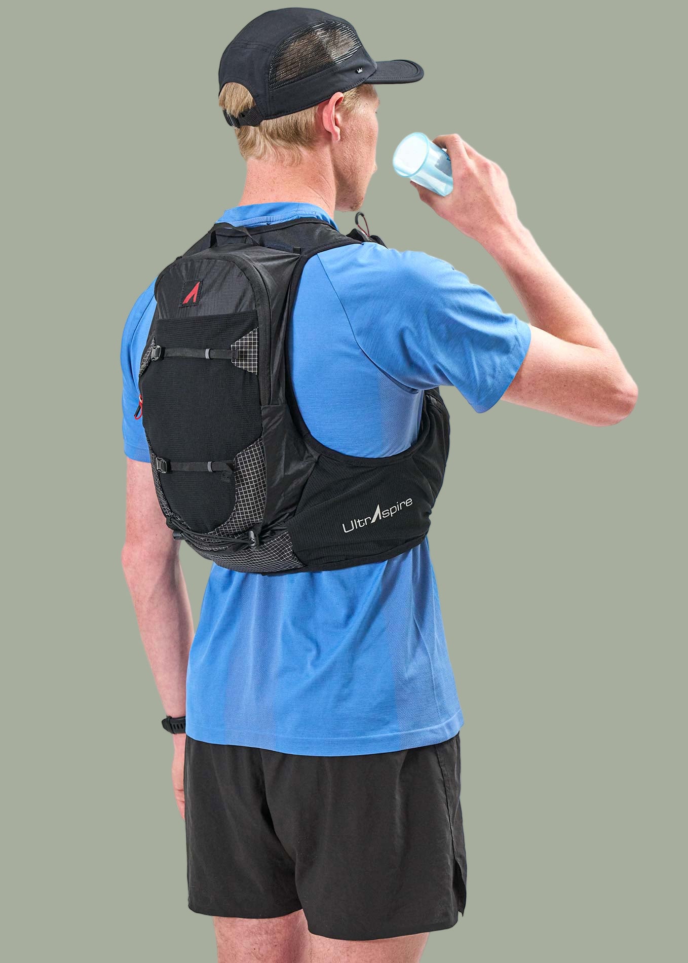 Person wearing a black Zygos V6 hydration vest and blue shirt, holding a C2 Race Cup.
