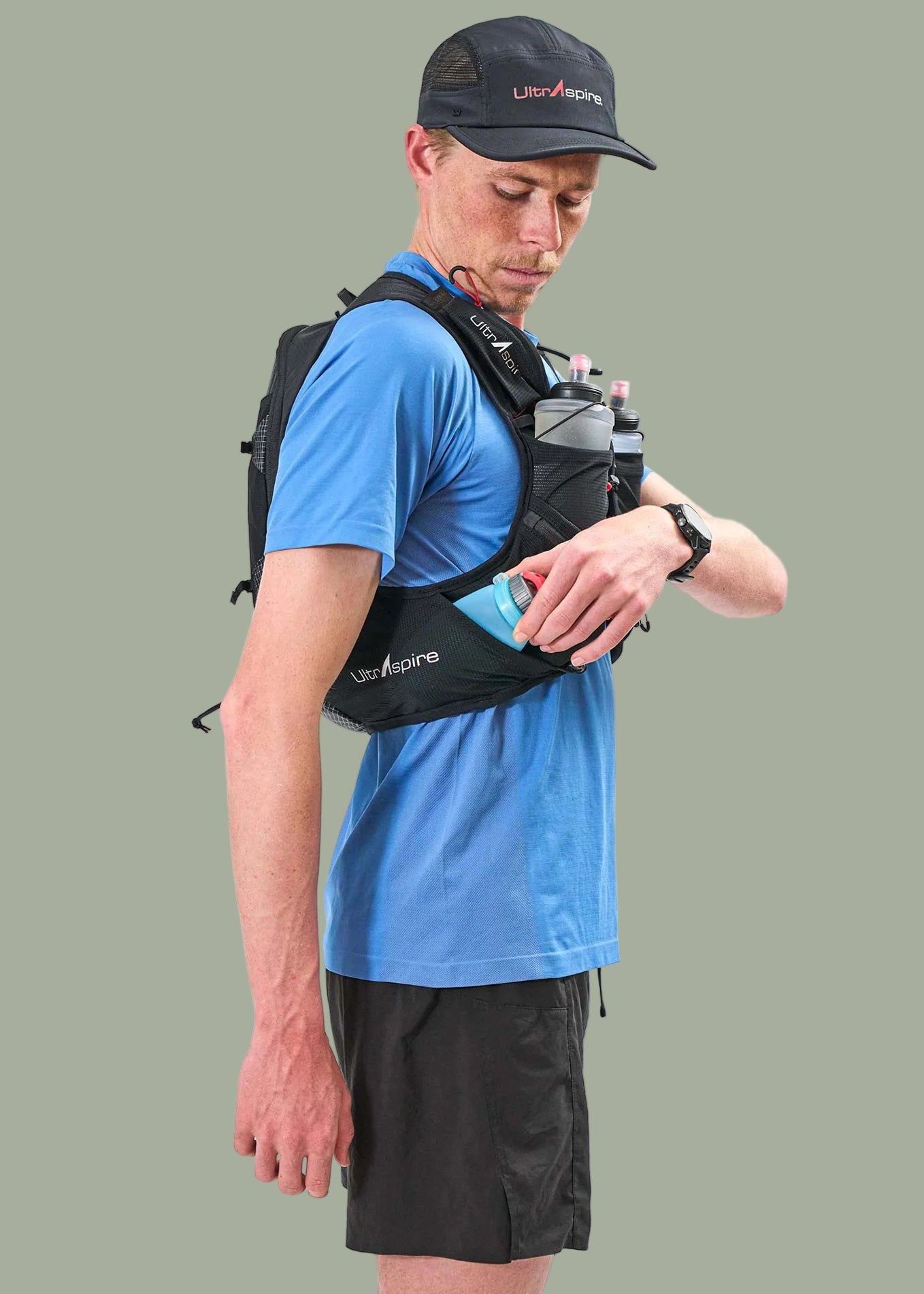 Person wearing a blue athletic shirt, black shorts, and a black Ultraspire Zygos V6 backpack with visible branding on the side.