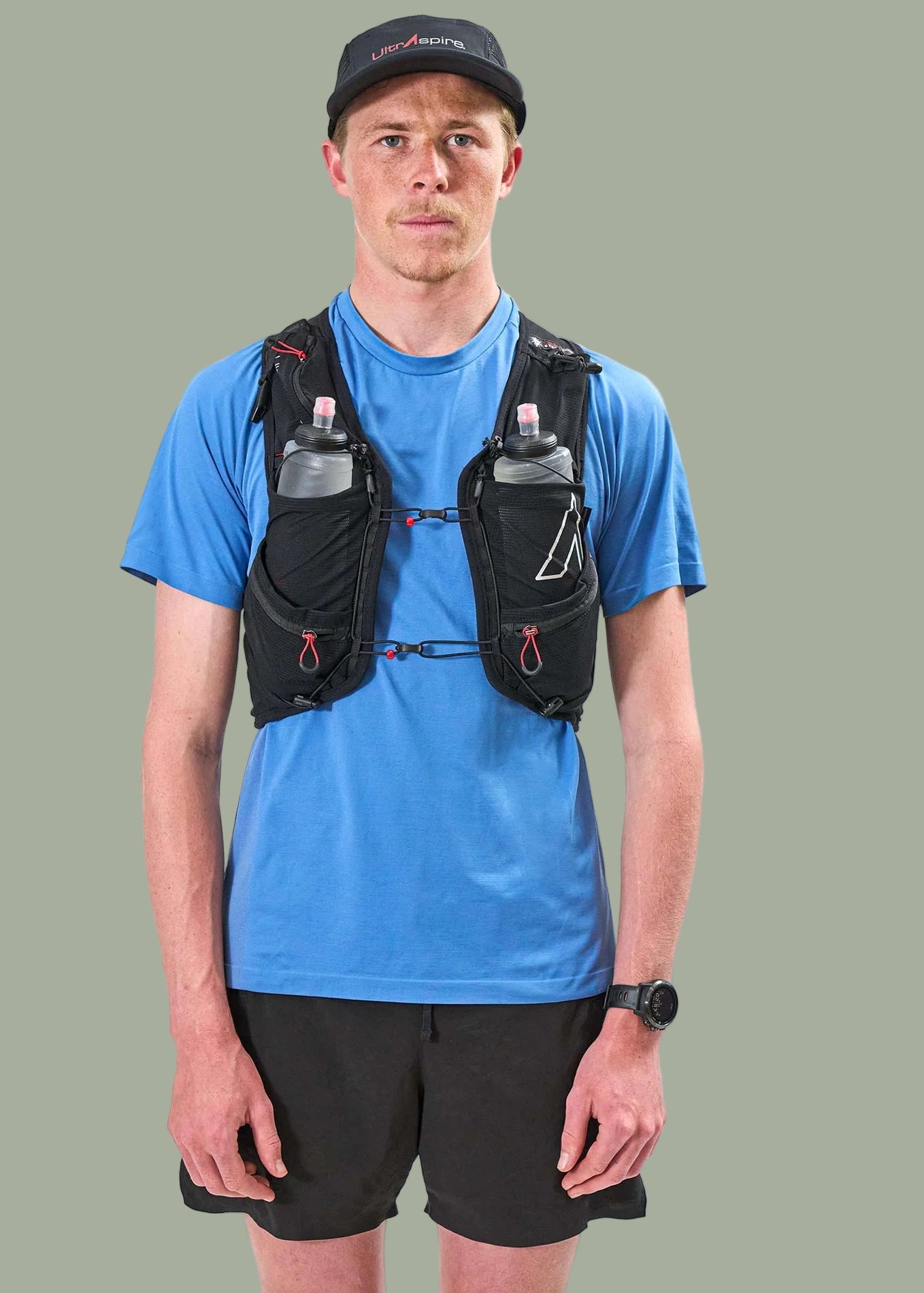 Person wearing a blue t-shirt and black Ultraspire Zygos V6 running vest with water bottles 